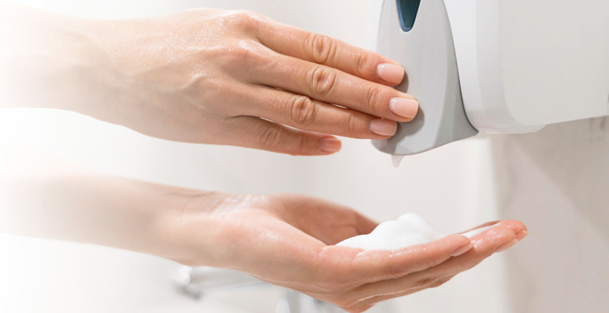 The Initial Singapore manual soap dispenser in use, demonstrating its touchless, hygienic operation.