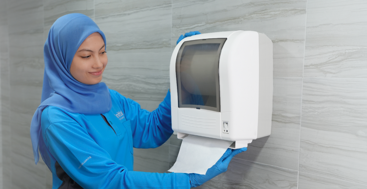 A sleek, wall-mounted automatic paper towel dispenser shown in a clean, professional washroom | Initial Singapore